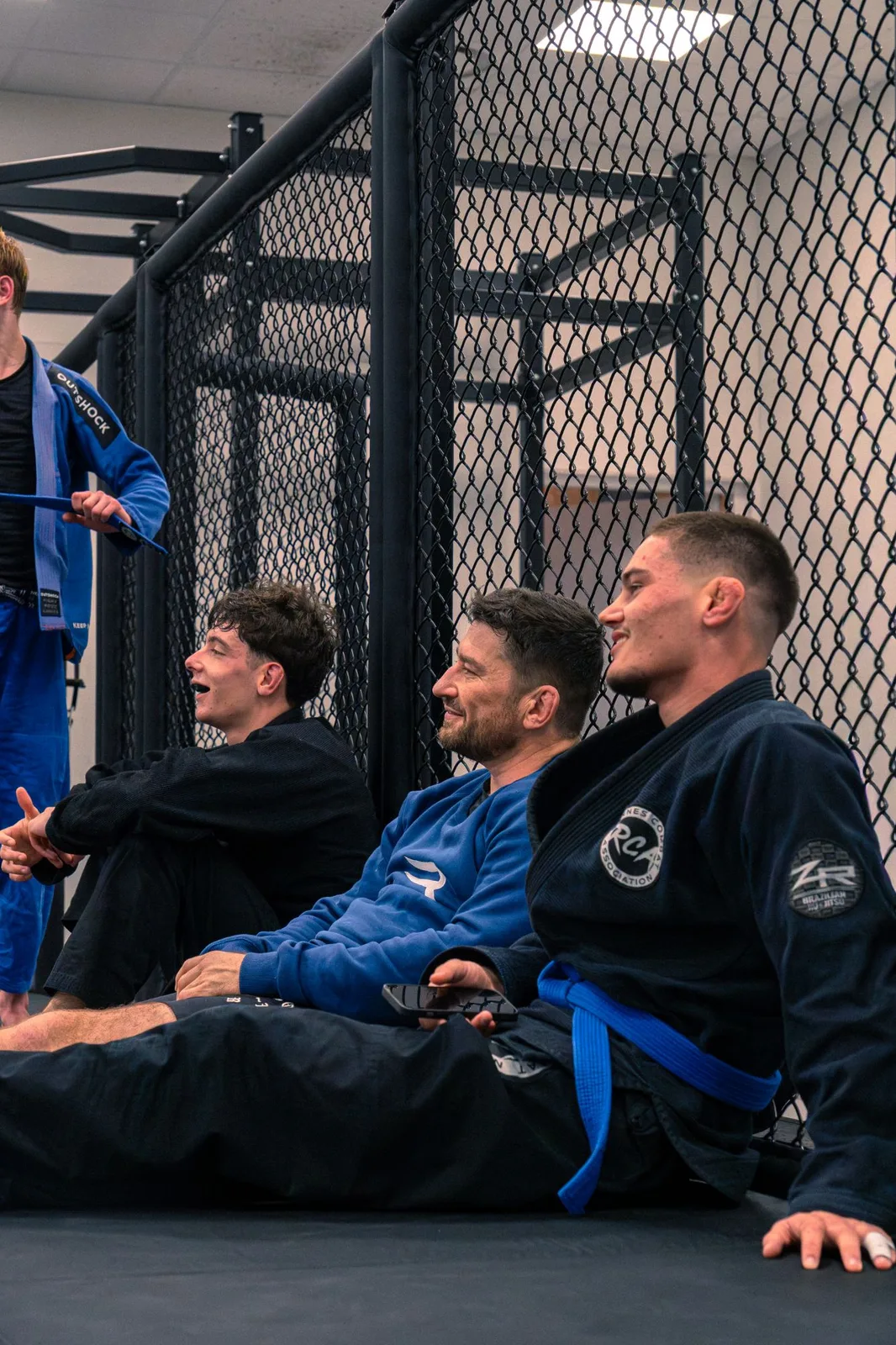 Pratiquants en kimono assis au bord du tatami du Rennes Combat Association, entre deux rounds