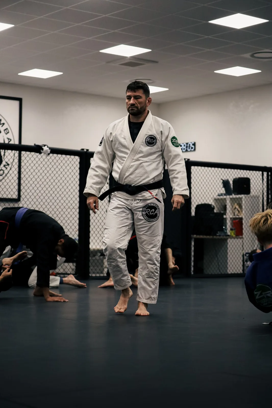 Coach ceinture noire encadrant un cours de jiu-jitsu brésilien sur les tatamis du club